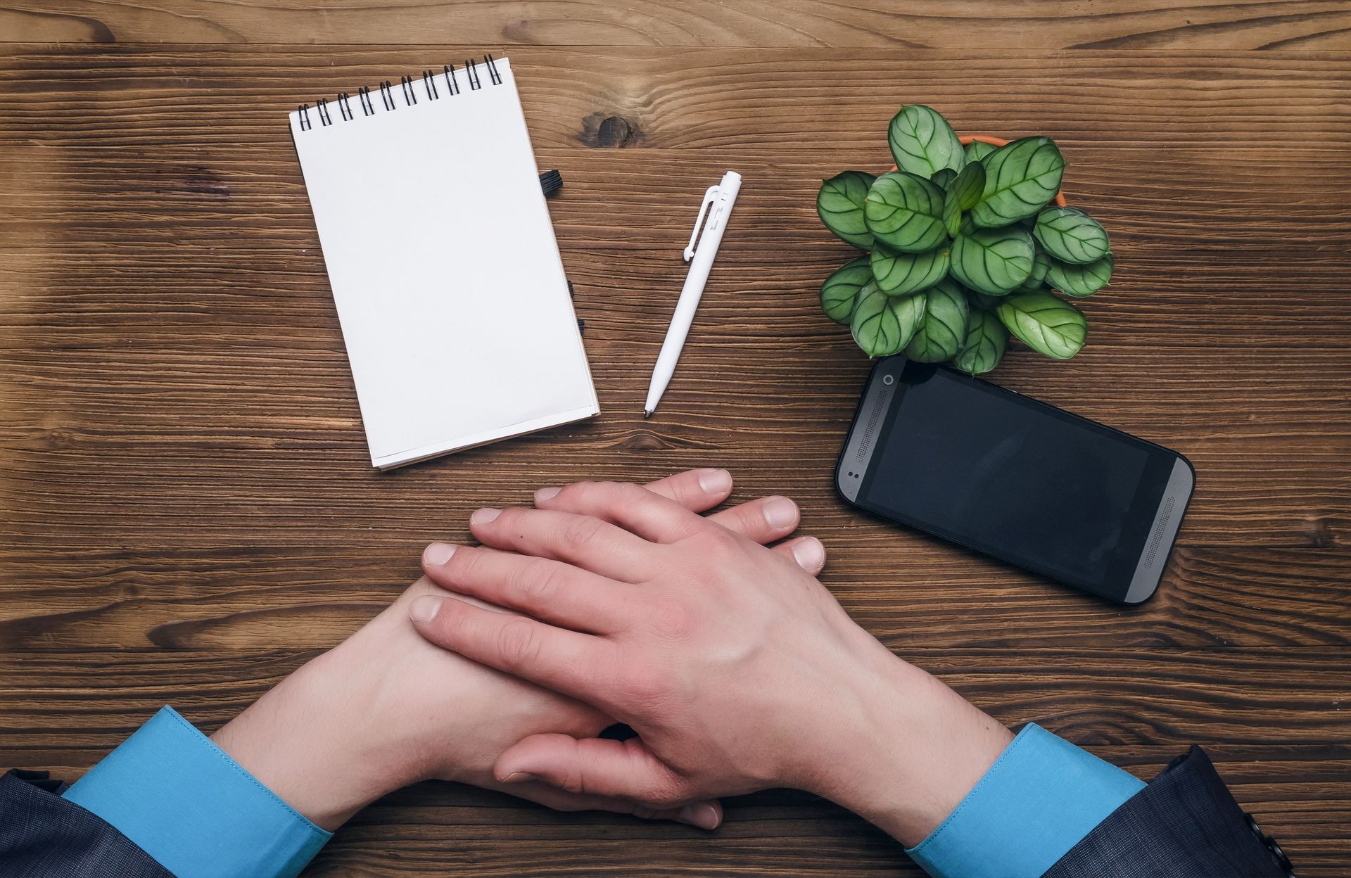 Businessman hands, mobile phone and notepad with blank sheet on wooden office desk table background. Contact us. Businessman hands, mobile phone and notepad with blank sheet on wooden office desk table background. Contact us.